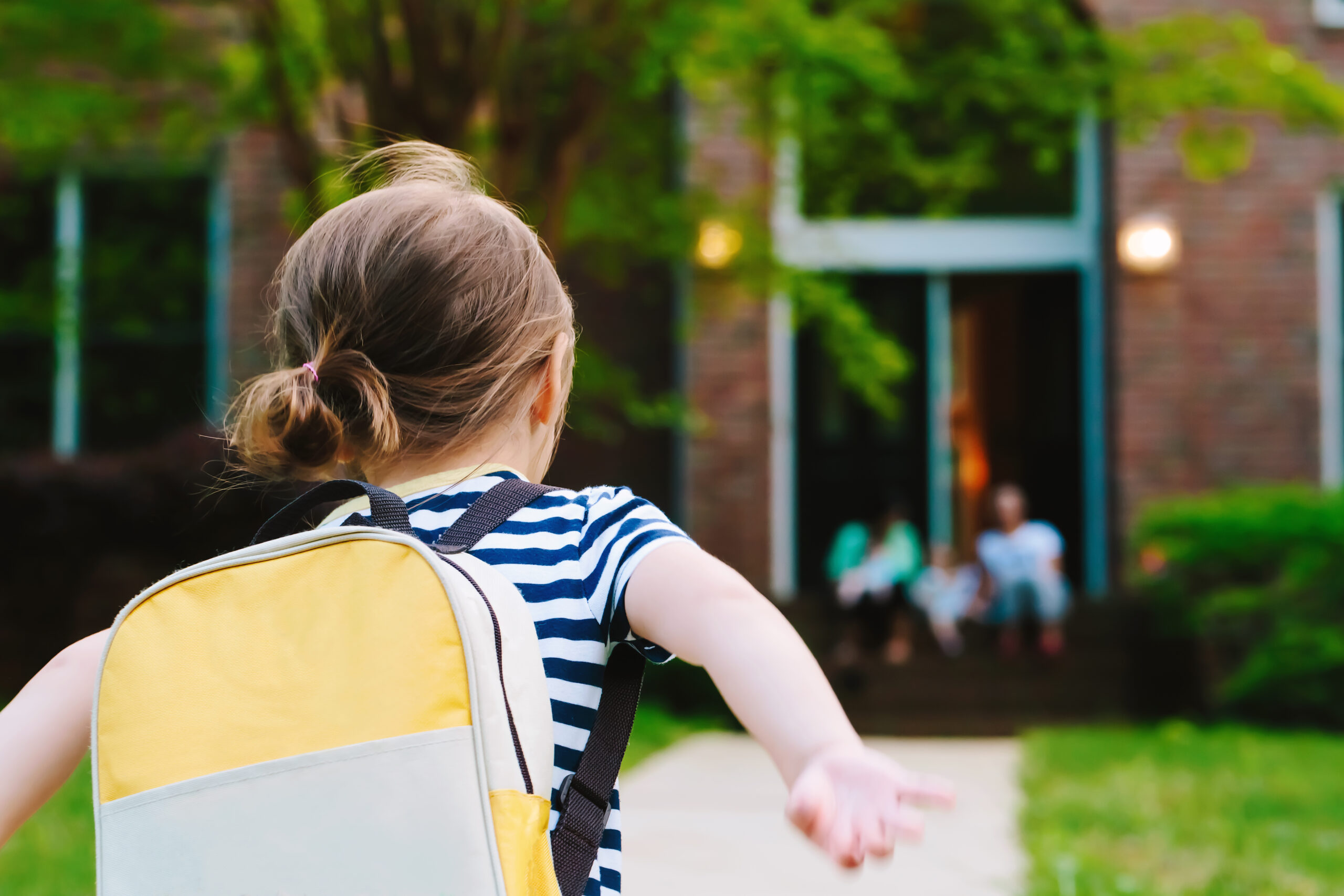 Happy Toddler girl arriving home from school with a backpack